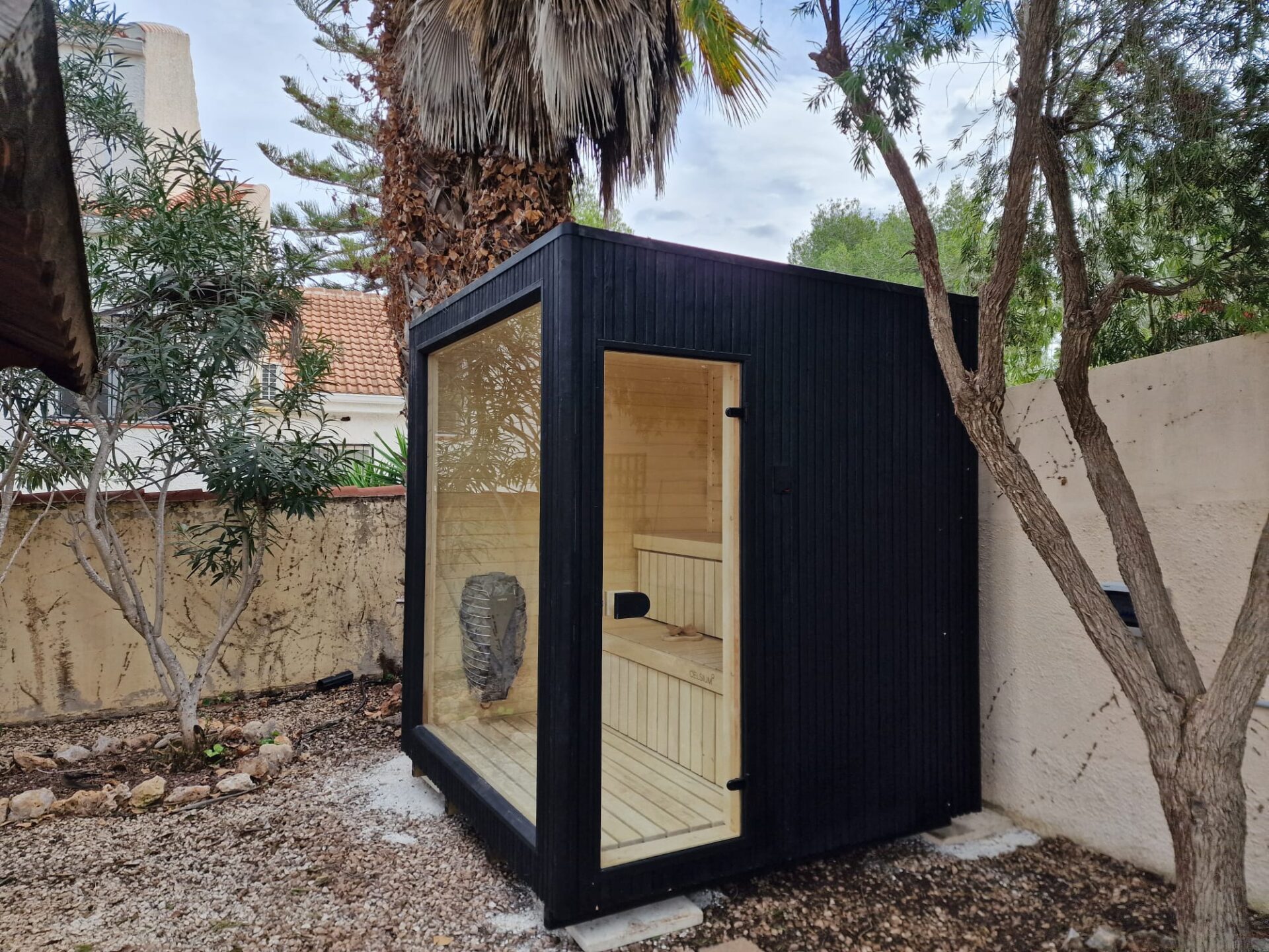 A modern Celsium Wellness sauna surrounded by lush greenery and calm outdoor living