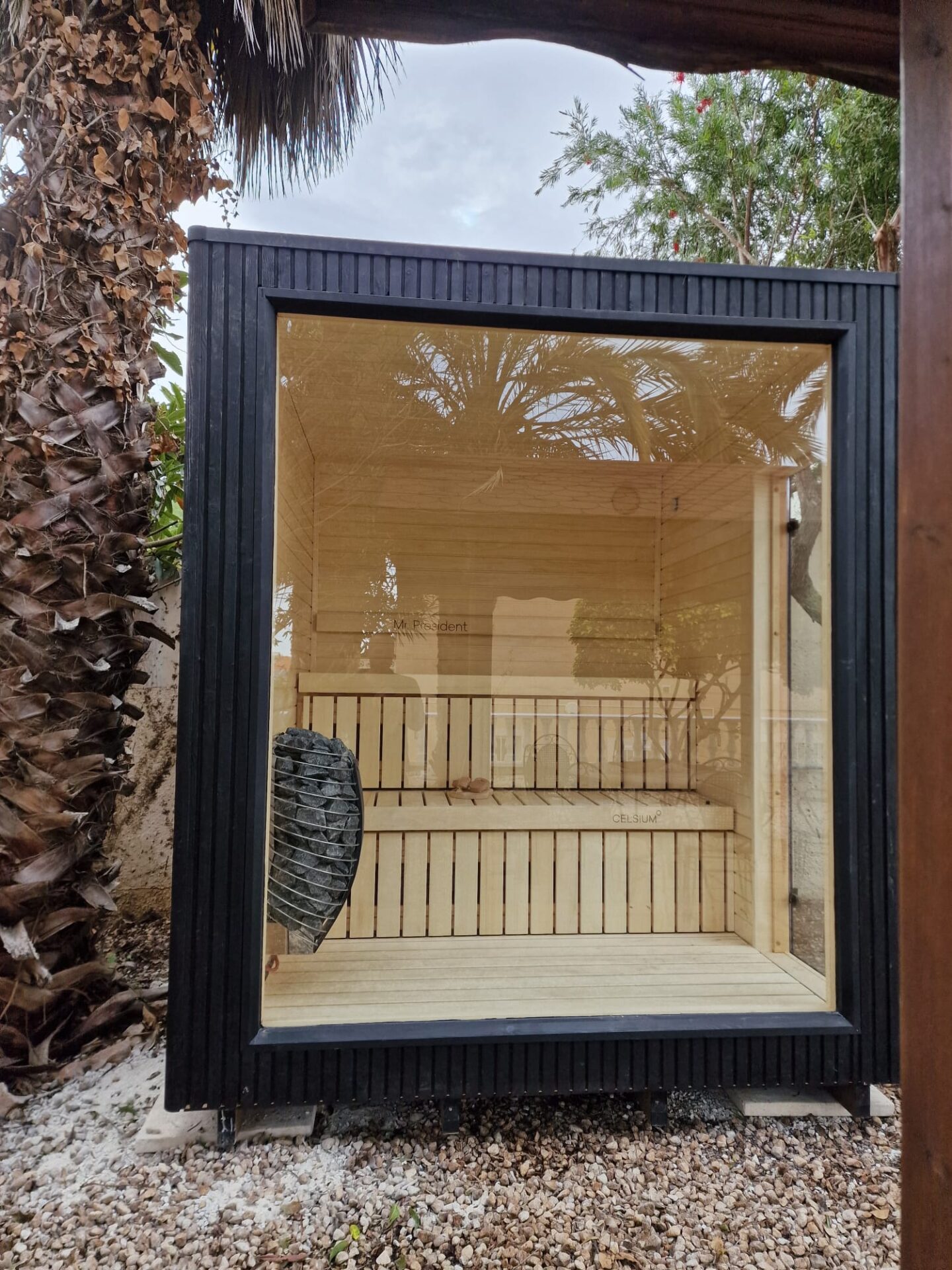 A modern Celsium Wellness sauna surrounded by lush greenery and calm outdoor living